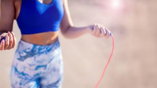 Rope Skipping Sportlerin in blauer Kleidung hält ein Springseil in den Händen