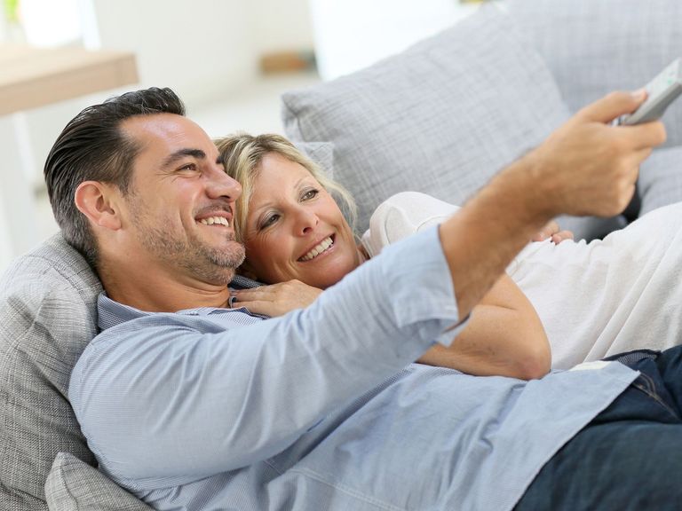 Ein Paar liegt auf der Couch und sieht gemeinsam fern