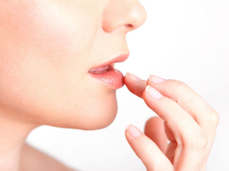 Frau cremt sich die Lippen ein