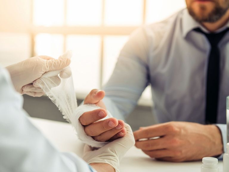 Arzt verbindet die Hand eines Patienten