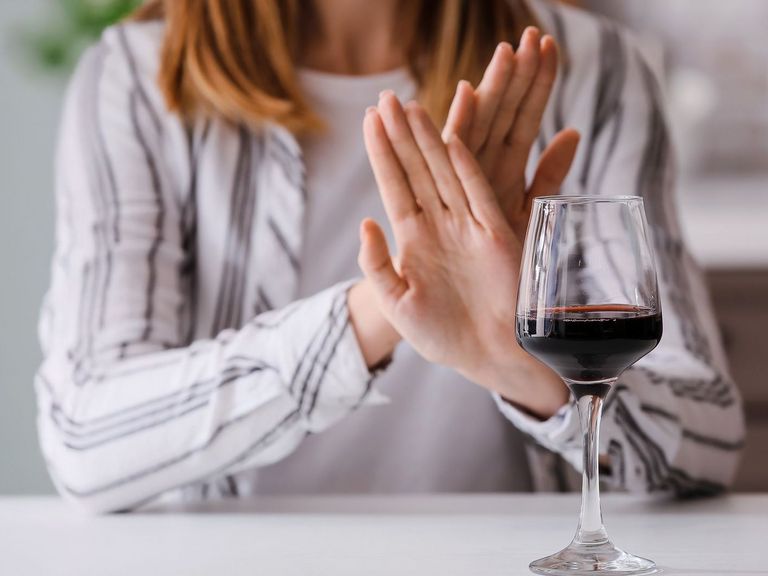 Frau verschränkt die Hände gegenüber einem Weinglas