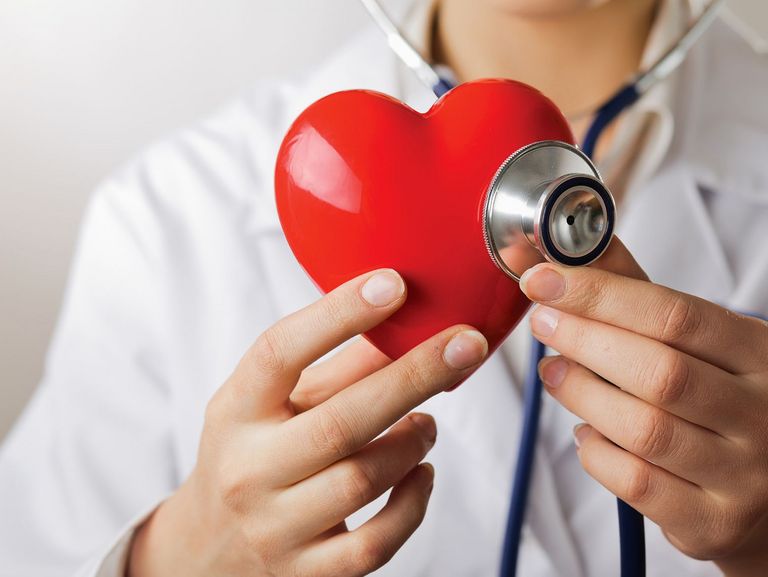 Arzt hält ein Stetoskop an ein Herz-Modell
