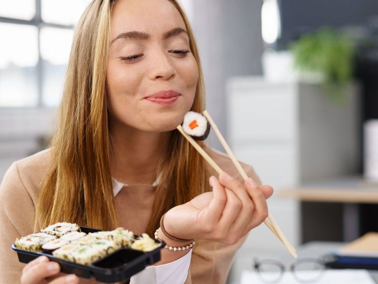 Frau genießt Sushi mit Essstäbchen
