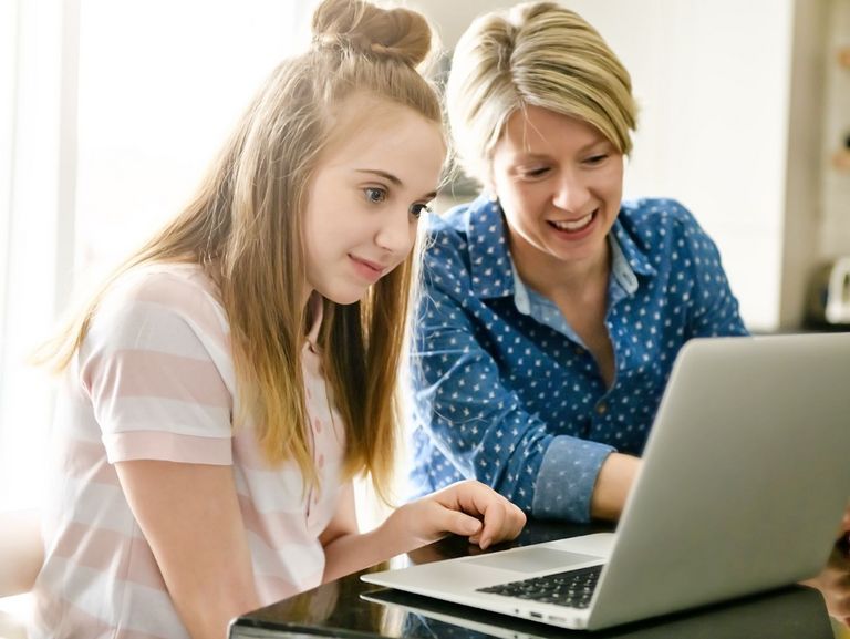 Jugendliche schaut mit Hilfe ihrer Mutter auf einen Laptop-Bildschirm