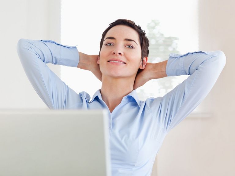 Frau streckt sich an ihrem Bildschirmarbeitsplatz