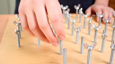 Mann übt in der Ergotherapie am Schraubbrett