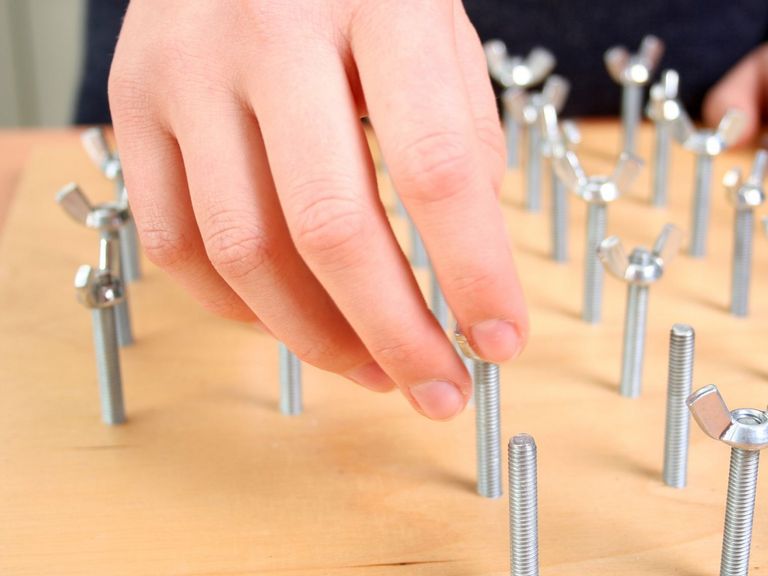 Mann übt in der Ergotherapie am Schraubbrett