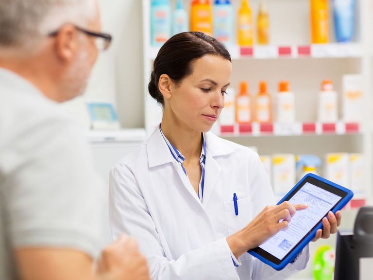 Apothekerin erklärt auf einem tablet einem Kunden das Elektronische Rezept