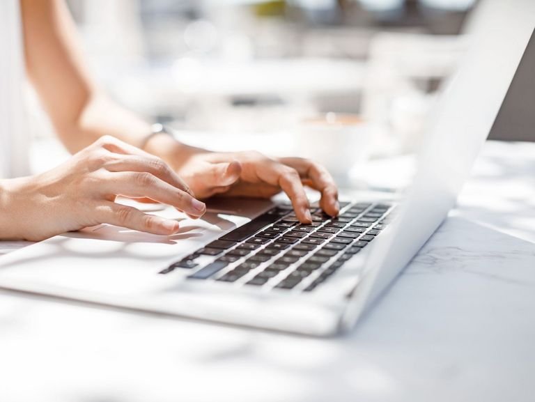 Frauenhände, die auf einer Laptop-Tastatur einen Text tippen