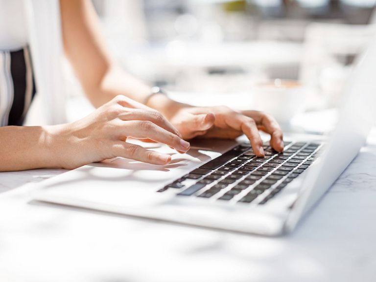 Frauenhände, die auf einer Laptop-Tastatur einen Text tippen