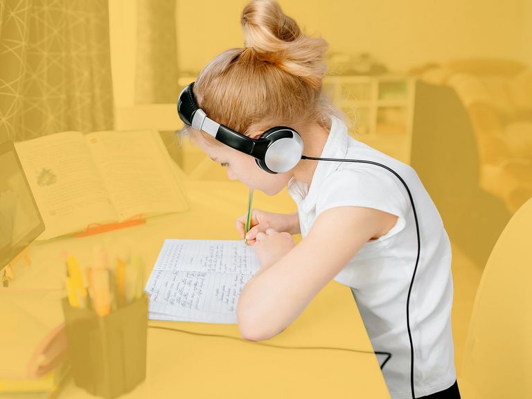 Schülerin am Schreibtisch mit einem Tablet und Kopfhörern