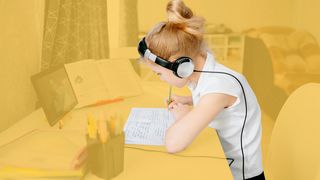 Schülerin am Schreibtisch mit einem Tablet und Kopfhörern