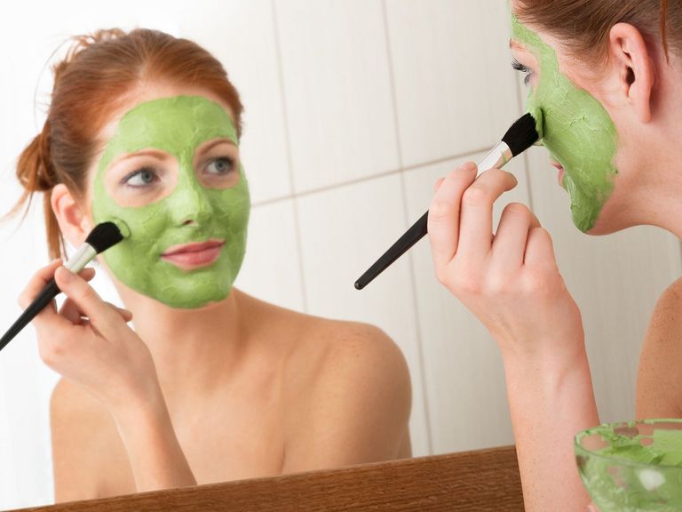 Frau trägt eine grüne Gesichtsmaske auf