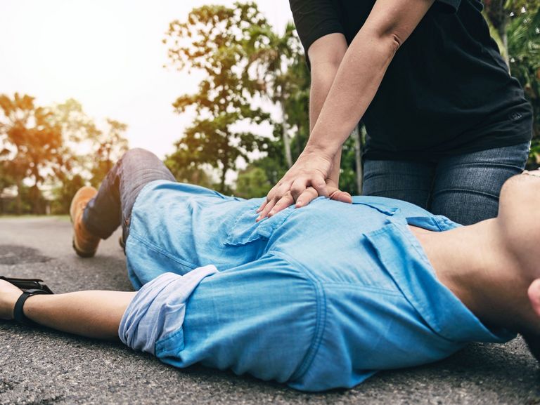 Wiederbelebung mit Herzdruckmassage bei einem Mann, der auf der Straße liegt