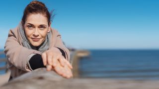 Frau im Portrait auf einer Seebrücke an einem Strand bei Sonnenschein