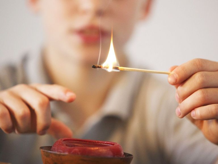 Junge spielt mit einem brennenden Streichholz