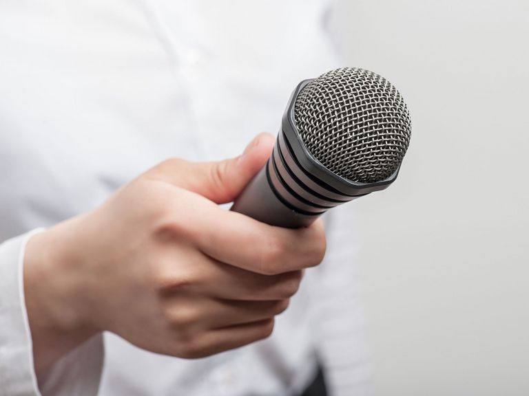 Eine Frauenhand hält ein Mikrofon in Richtung Kamera