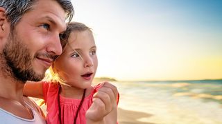 Vater mit kleiner Tochter auf dem Arm am Strand