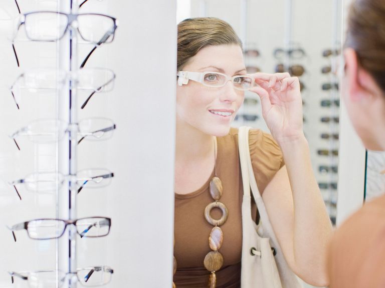 Frau sucht testet eine Brille im Spiegel