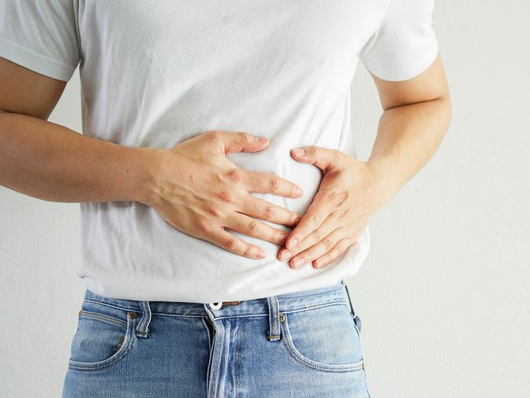 Mann hält die Hände auf seinen Bauch aufgrund von Schmerzen im Darm