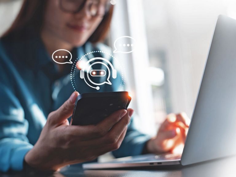 Frau mit Smartphone und Laptop nutzt eine KI