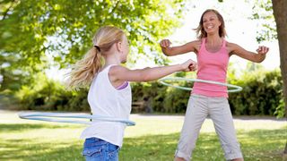 Mutter und Tochter üben mit einem Hula-Hoop-Reifen