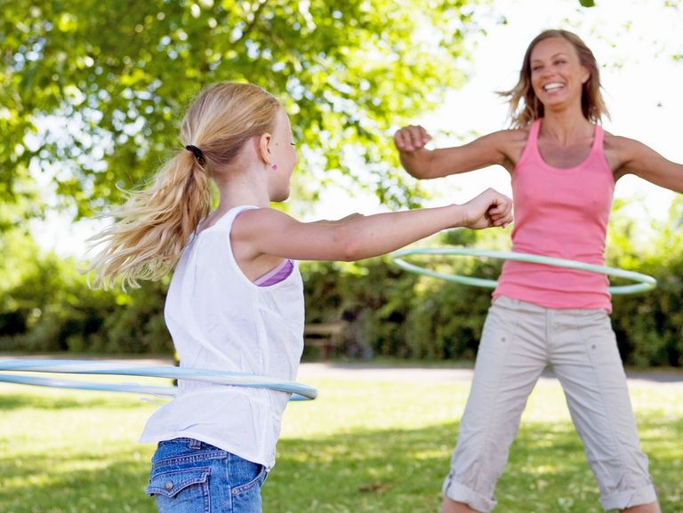 Mutter und Tochter üben mit einem Hula-Hoop-Reifen