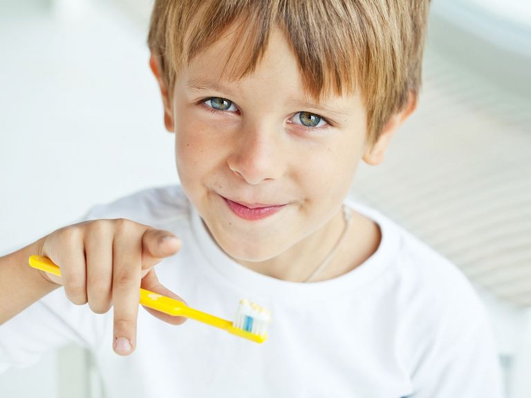 Junge mit einer Zahnbürste in der Hand zeigt in die Kamera