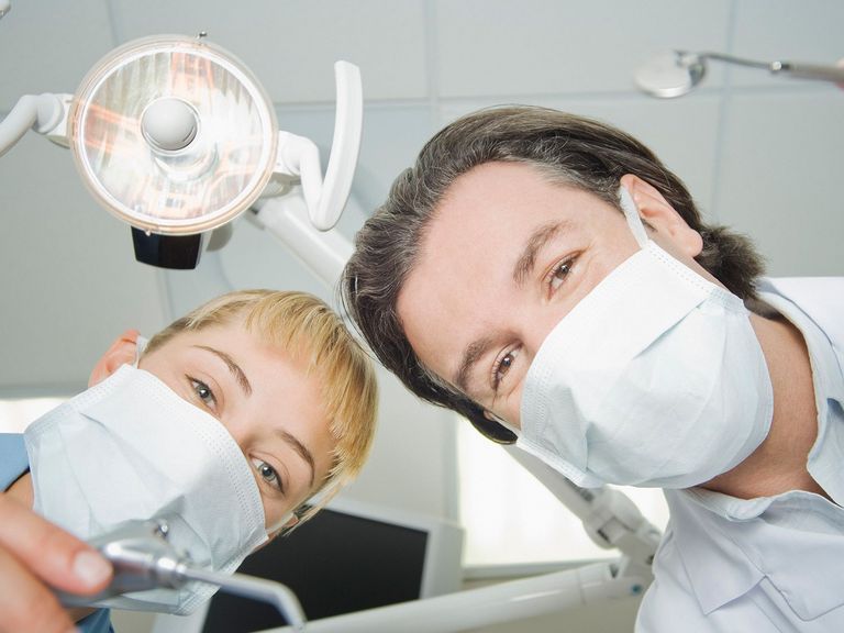 Zahnarzt und Zahnarzthelferin schauen in die Kamera