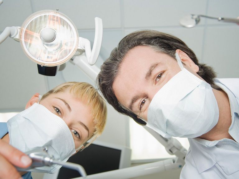 Zahnarzt und Zahnarzthelferin schauen in die Kamera