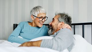 Schlafgeheimnisse Pärchen liegt im Bett und lacht sich an