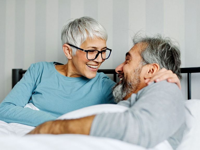 Pärchen liegt im Bett und lacht sich an