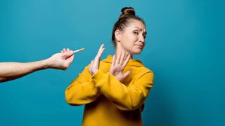 Weltnichtrauchertag Männlicher Arm reicht einer Frau eine Zigarette, die diese jedoch vehement und mit deutlicher Körpersprache ablehnt