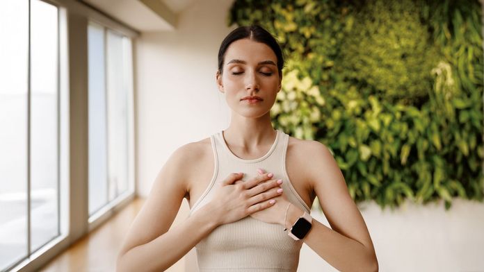 Richtig Atmen Frau in einem Zimmer, die beide Hände flach auf der Brust hat und bewusst atmet