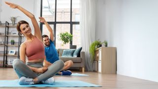 Bonusprogramm AchtzehnPlus Pärchen im Schneidersitz auf Yogamatten macht Dehnübungen