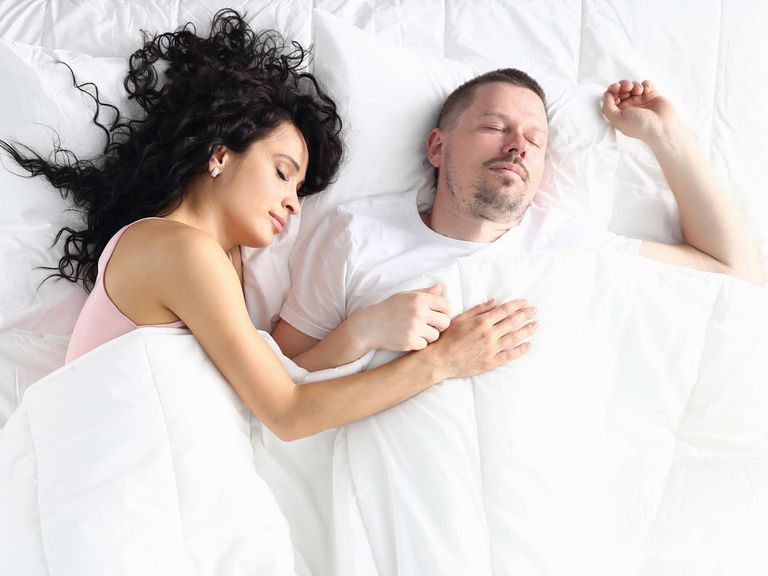 Pärchen liegt schlafend in weißer Bettwäsche