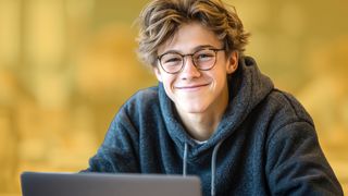 Schüler mit Brille vor einem Laptop sitzend