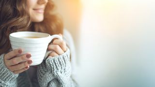 Wintergetränke Frau in dickem Pullover und einer Tasse mit einem Heißgetränk in der Hand