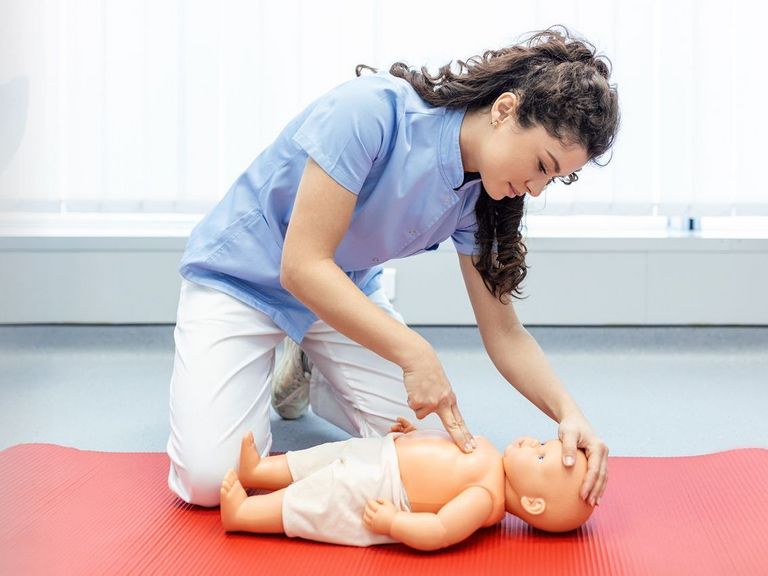 Krankenschwester zeigt beispielhaft zwei Erste-Hilfe-Maßnahmen am Säugling