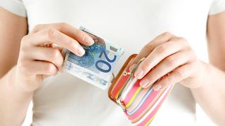 Frau steckt 20 Euro in eine Geldbörse