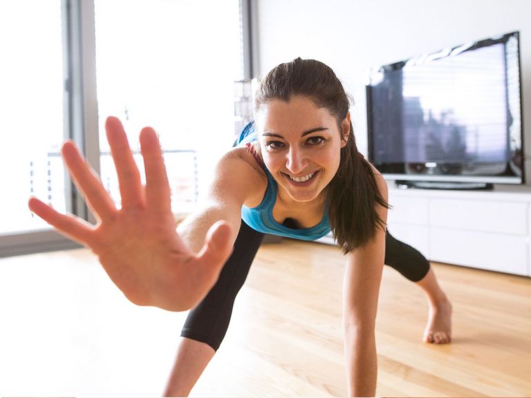 Junge Frau treibt Sport im Wohnzimmer