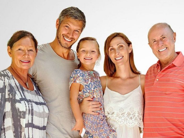 3-Generationen-Familie in Sommerkleidung vor einem grauen Hintergrund