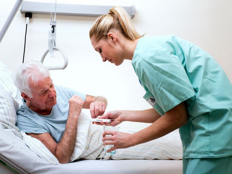 Krankenschwester versorgt einen Pflegebedürftigen mit seinen Medikamenten