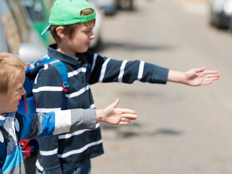 Kleine Schulkinder wollen eine Straße überqueren