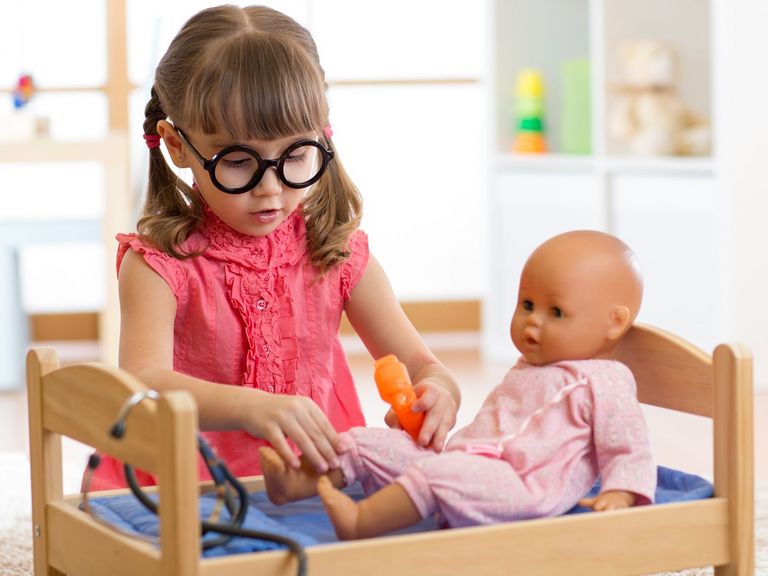 Kleines Mädchen spielt Puppendoktor