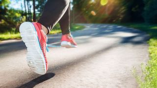 Lauftraining Füße einer aktiven Joggerin auf einer Landstraße
