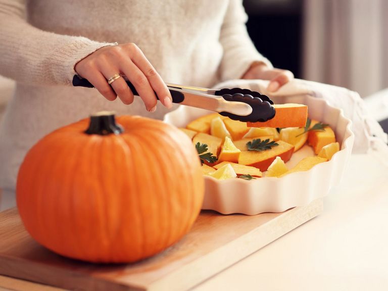 Frau bereitet Kürbis in einer weißen Auflaufform zu