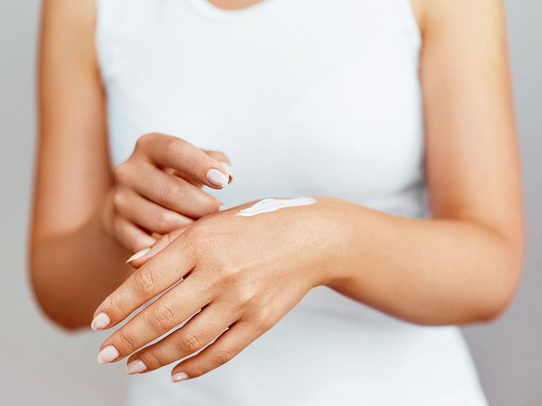 Frauenhände, die eingecremt werden