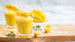 Zwei Gläser mit Mango-Lassi und Mangostücken als Deko