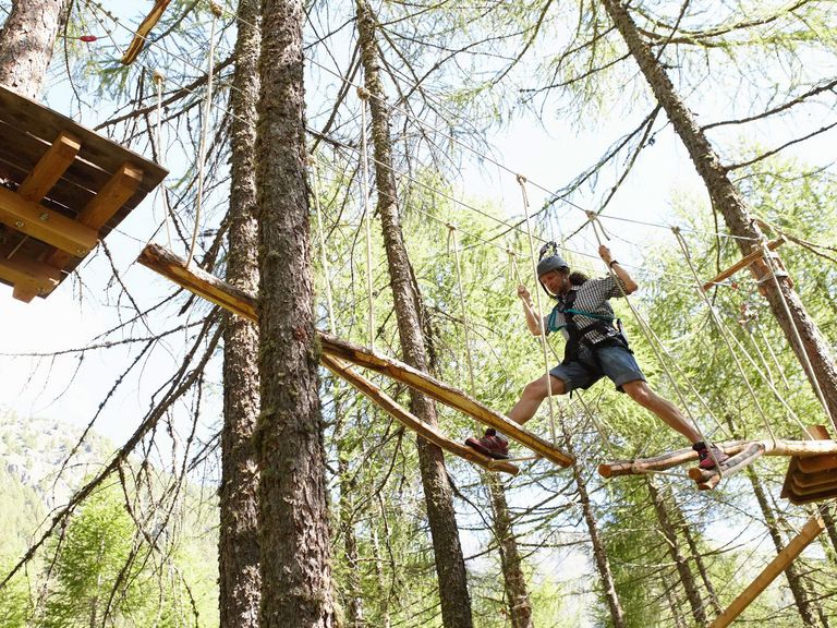 Mann bewältigt einen Parcours in einem Hochseilgarten